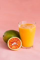 Glasses of mango, orange juice on pink background.
