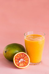 Glasses of mango, orange juice on pink background.