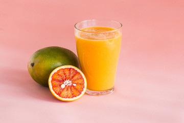 Glasses of mango, orange juice on pink background.
