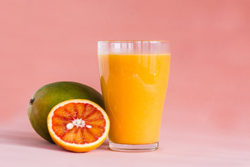 Glasses of mango, orange juice on pink background.