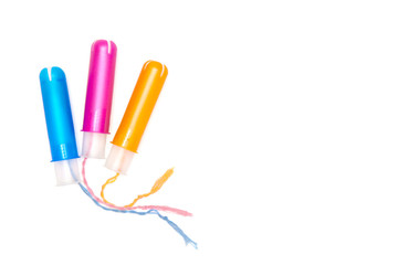 three cotton tampons with blue pink yellow applicartors isolated on white background. Menstrual cycle period concept. Woman days hygiene protection. Top view, flat lay. copyspace