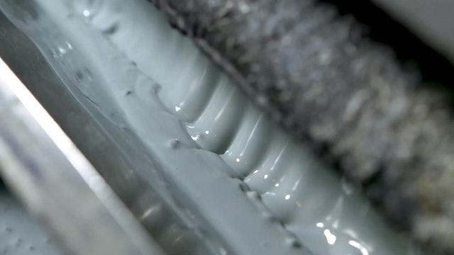 Panning extreme closeup of bubbling light green-grey paint in an old and grungy wallpaper printer