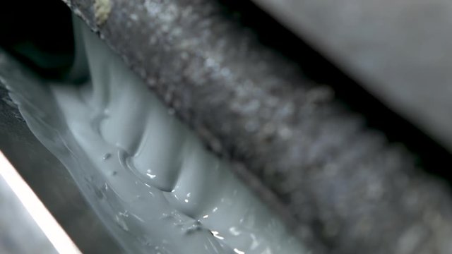 Panning extreme closeup of bubbling light green-grey paint in an old and grungy wallpaper printer