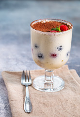 Tiramisu dessert in glass with cocoa powder and berries