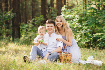 Happy young family spends time together in nature. Picnic in the forest