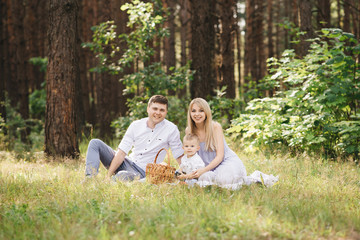 Fototapeta premium Happy young family spends time together in nature. Picnic in the forest