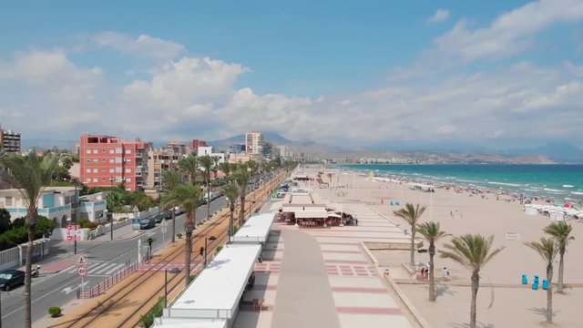 Ascending Aerial footage of San Juan beach in Alicante Spain, with mountains in the background, flying over tourism info point