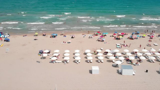 Aerial footage of the beach umbrellas and surf board rental at Alicante Beach, moving sideways