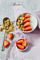 Breakfast with muesli, strawberries and yogurt. Grey background, top view