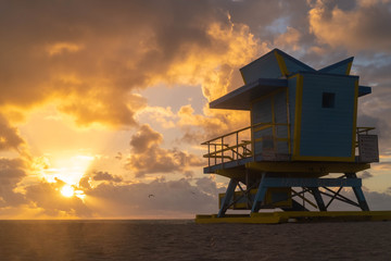 Blue Beach hut on Miami Beach at Sunrise with epic cloudscape and silhouette of seagulls flying in the sky