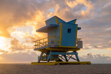 Blue Beach hut on Miami Beach at Sunrise with epic cloudscape and silhouette of seagulls flying in...