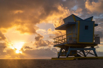 Blue Beach hut on Miami Beach at Sunrise with epic cloudscape and silhouette of seagulls flying in the sky
