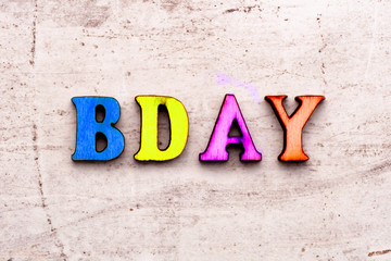 Inscription BD BDAY birthday COLORED abbreviation in wooden letters on a light background
