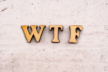 Inscription wtf What is Terrible Failure, Internet Slang, COLORED abbreviation in wooden letters on a light background