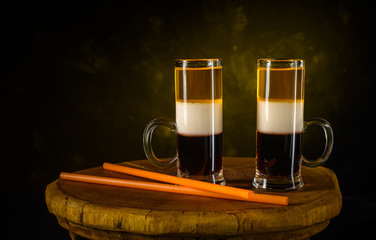 Two B-52 cocktails shot and sraws on wooden vintage tray with dark gray concrete background