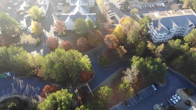 Apartment complex morning. Aerial pull back tilt. Car driving through neighborhood. Sun flares.