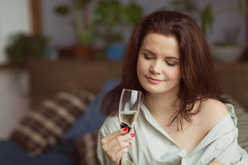 Attractive young woman in men's shirt drinking champagne