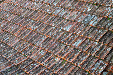 Old red ceramic tile on the roof in need of repair.