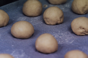 Fototapeta na wymiar Small Bread Dough Balls Placed on Cooking Paper on Pan - Ready to be Baked, Kitchen Set