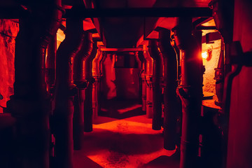 Steel pipes of ventilation system in Soviet nuclear bunker in red light as abstract industrial corridor or tunnel with special equipment