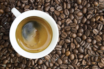 White coffee cup with hot drink against coffee beans background