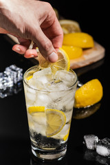 bartender hands making finish details for tasty Gin tonic mixed drink cocktail with lemon slices...