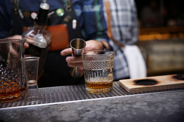 Bartender preparing tasty cocktail at counter in nightclub, closeup