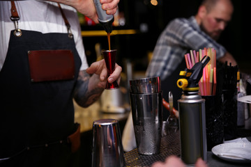 Bartender preparing tasty cocktail at counter in nightclub, closeup