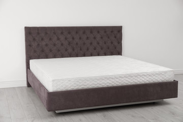Comfortable bed with new mattress near wall in room. Healthy sleep