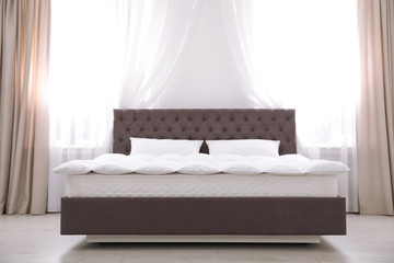 Comfortable bed with new mattress near window in room. Healthy sleep