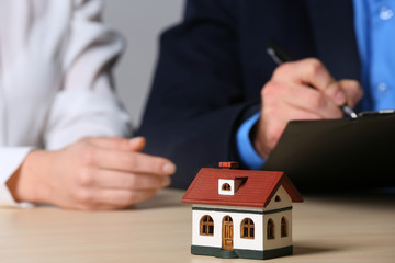 House model and real estate agent working with client at table, closeup. Home insurance