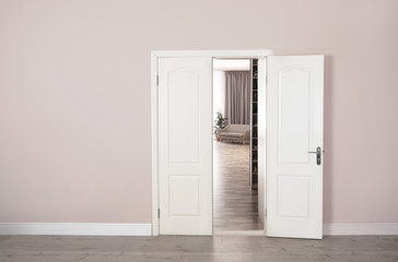 Open white door to stylish living room. Modern interior design