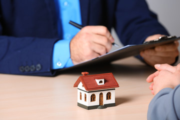 Real estate agent working with client at table in office, closeup. Home insurance