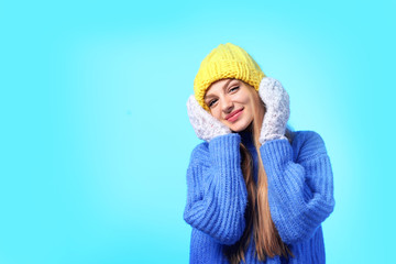 Portrait of emotional young woman in stylish hat, sweater and mittens on color background, space for text. Winter atmosphere