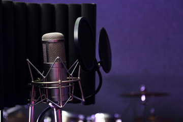 Condenser microphone in modern recording studio. Space for text