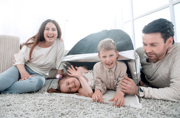 happy parents play with children in a tent in the living room