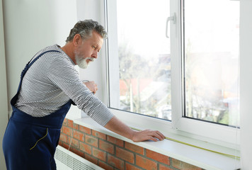 Fototapeta premium Service man measuring window for installation indoors