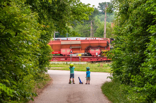 Kinder mit Rollern warten vor Bahn&uuml;bergang