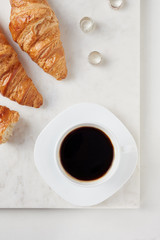 Croissants and a cup of coffee on the white marble board