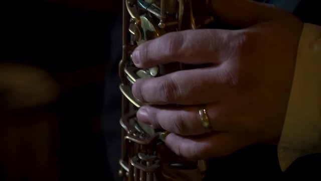 Close up of a saxophonist's hands playing the saxophone at a live event.