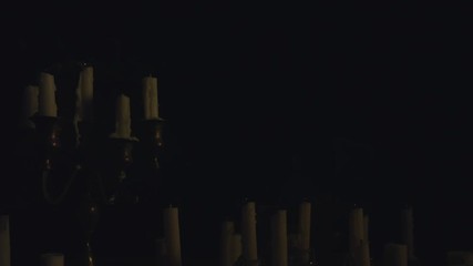 A group of white candles some on a candelabra lit up then blown out by a strong wind.
