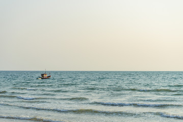 Fototapeta premium Single fishing boat float and drop anchor on the sea and background of sunset sky, view from a beach.