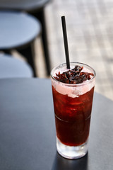 Cherish cocktail drink with dark straw on black table outdoors