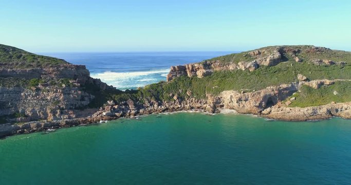 Aerial pull back of Robberg Nature Reserve, a beautiful rock mountain landscape surrounded by blue ocean.