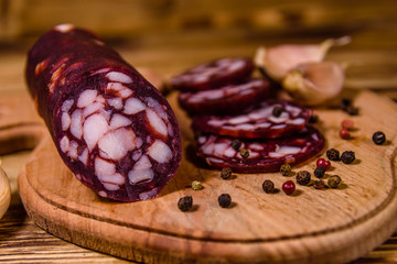 Cutting board with sliced salami sausage and garlic on a wooden table