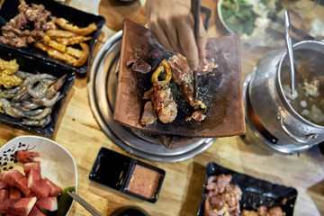 Visitor of traditional vietnamese restaurant cooking meat on hot pot