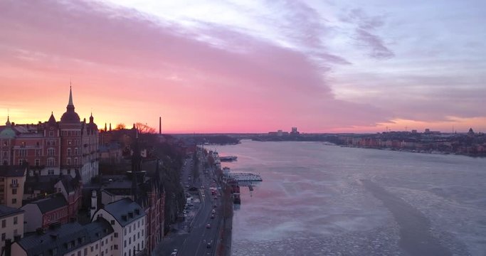 Beautiful cold aerial view Mariaberget Stockholm Sweden. Majestic golden pink colorful winter sunset. Amazing frozen urban view Sodermalm Riddarfjarden. 4K drone footage over city evening traffic.