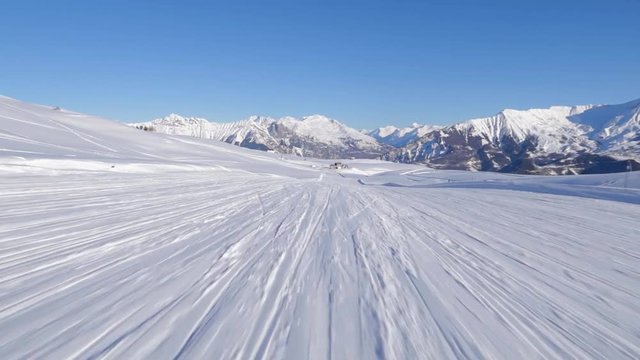 skiing first person point of view riding long white snowy track with clear blue sky