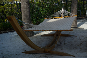 Hammock on a beach with palm trees surrounding it.