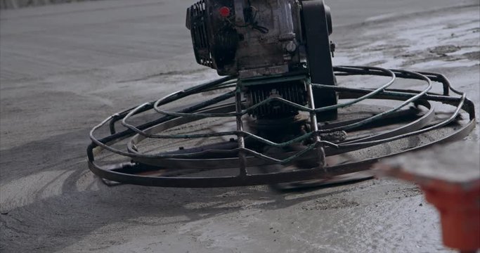 Slow motion close up of a concrete power trowel smoothing concrete at construction site view 2